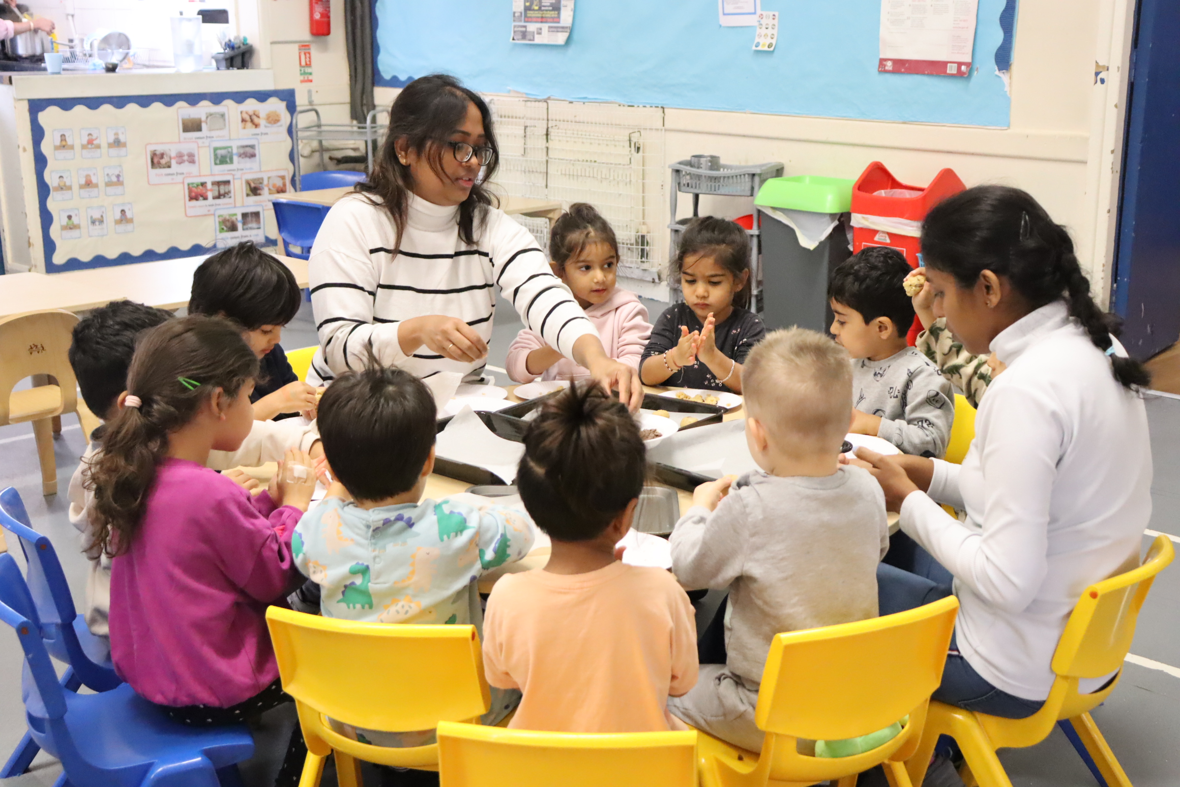 preschoolers gathering around two teachers whilst baking for baking week