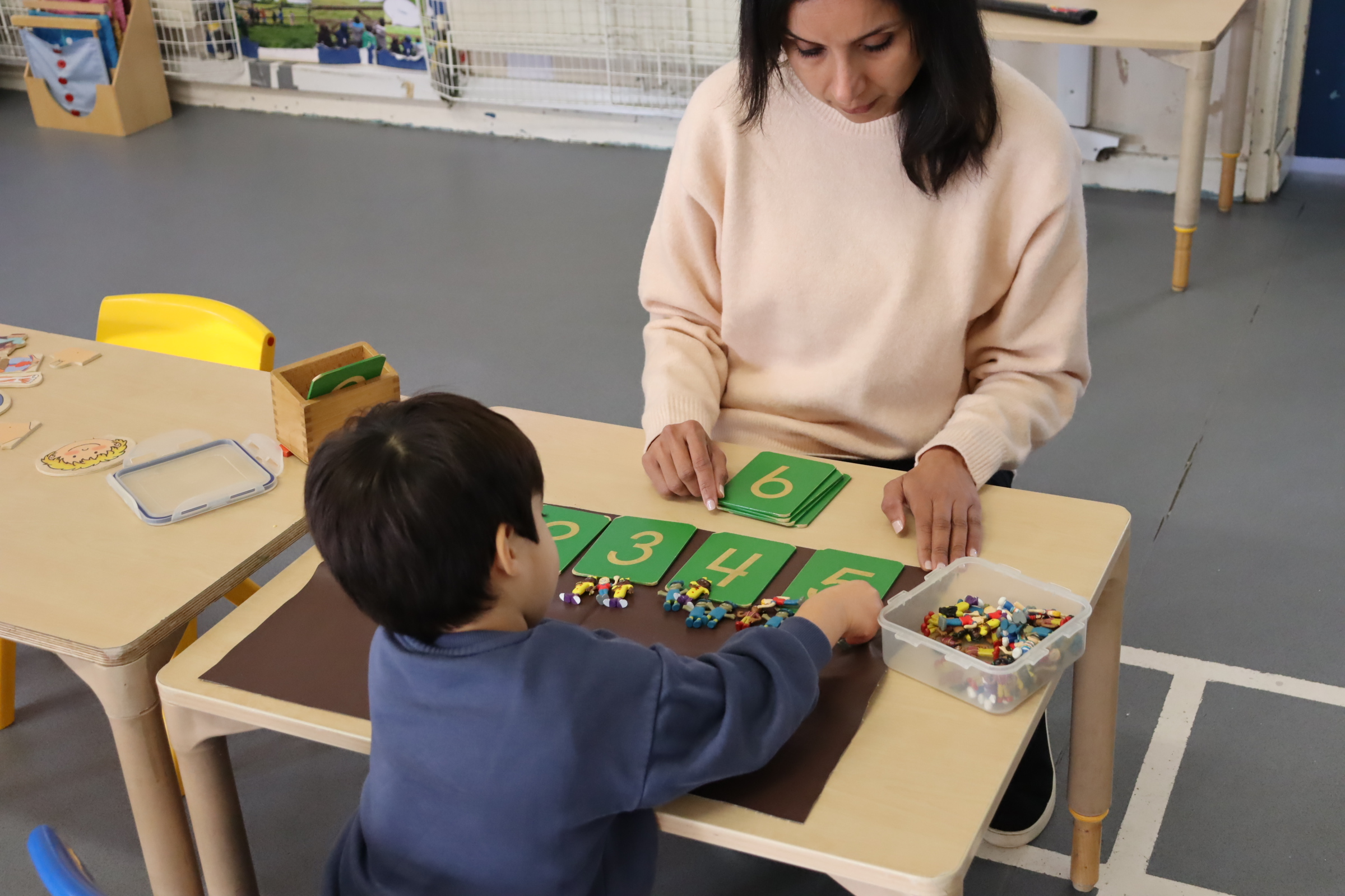 a teacher guiding one of the Budding Learner's preschooler while they are performing a mathematics Montessori activity