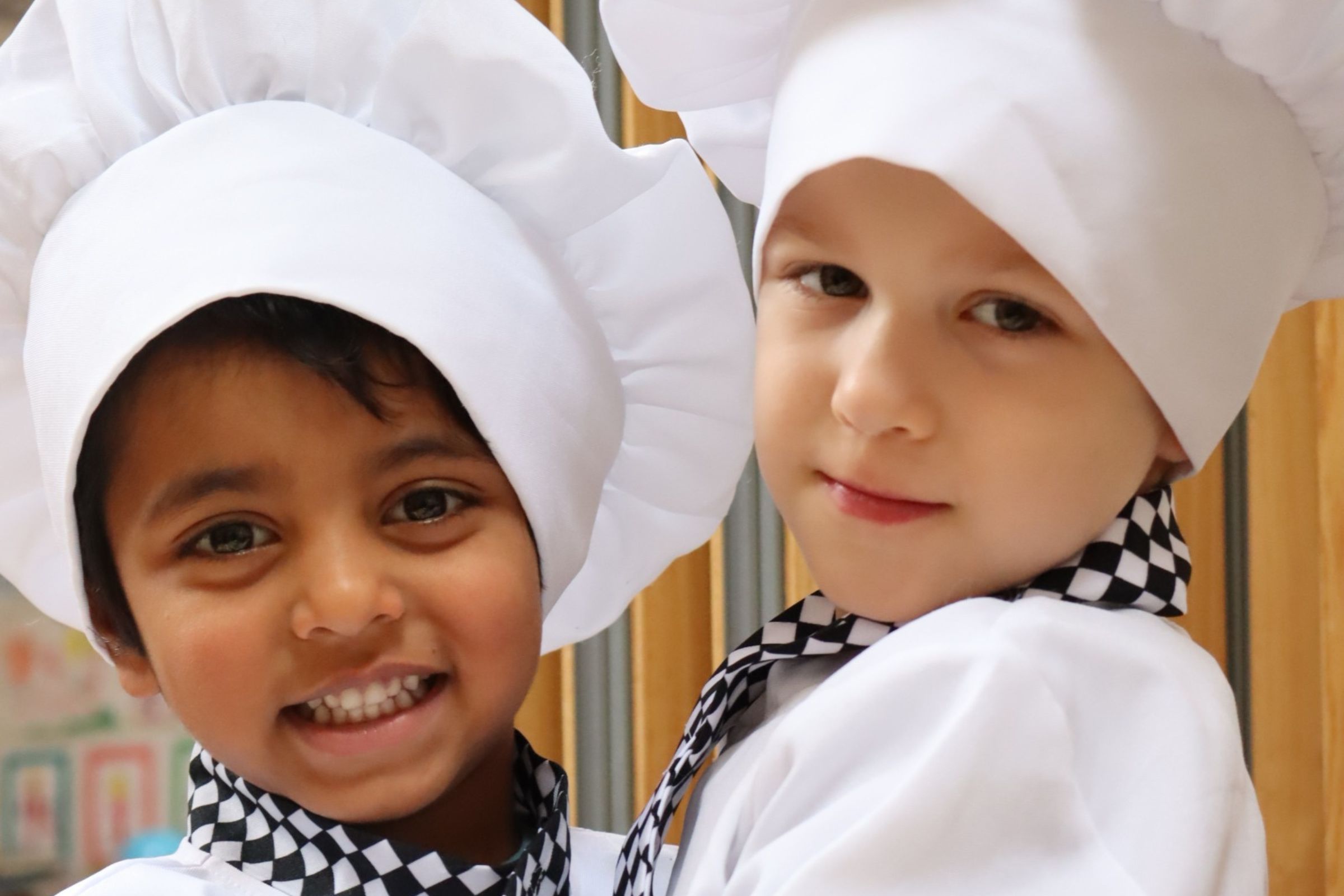 Two Great learners preschoolers dressed in chef uniforms, ready to serve their peers