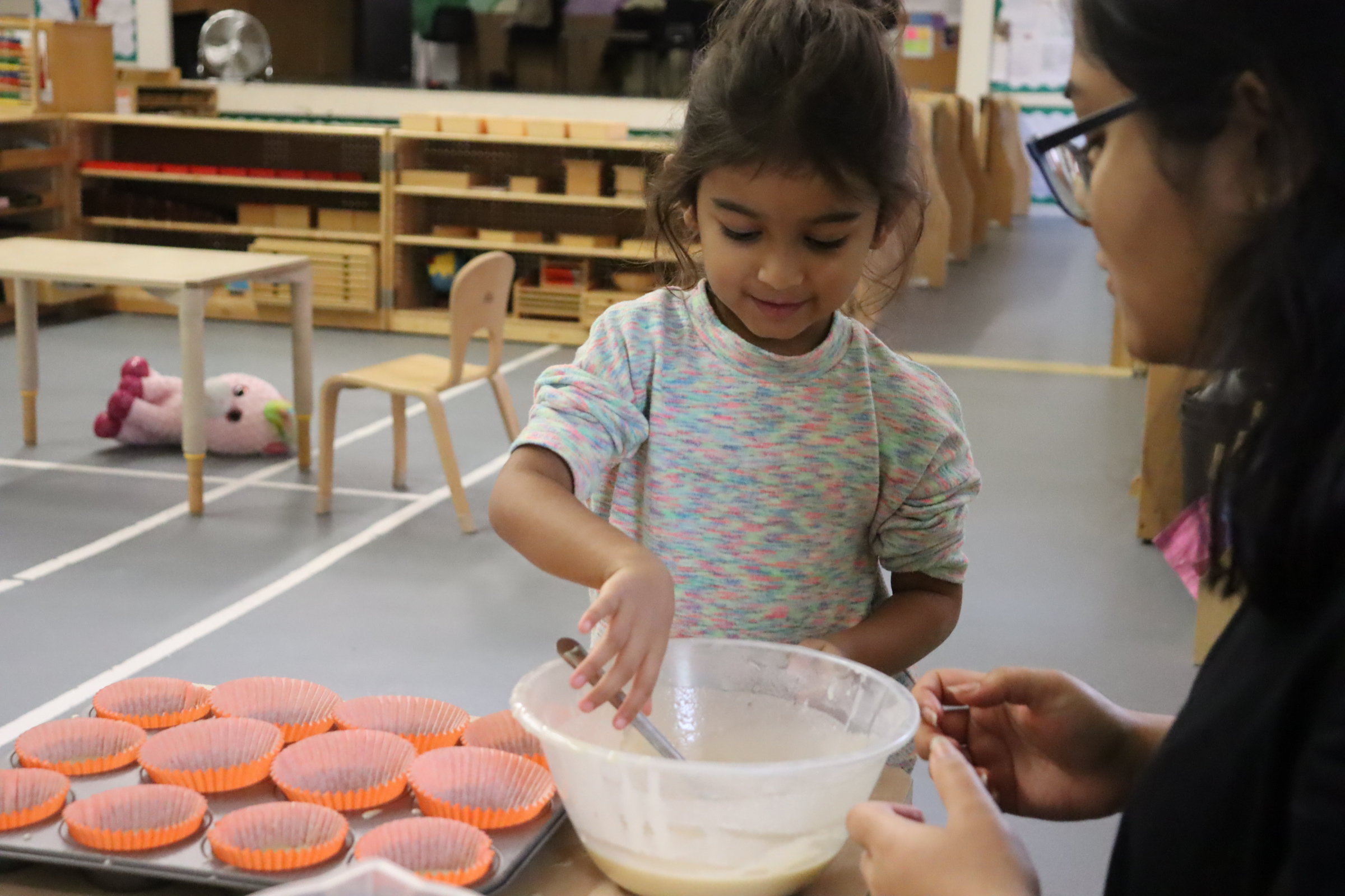 A Budding Learners' preschooler scooping up batter for cupcake
