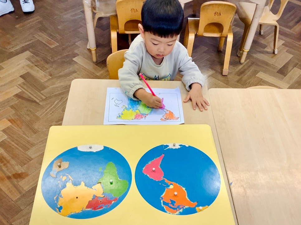 A Great learners' preschooler colouring the world map to identify the correct continents