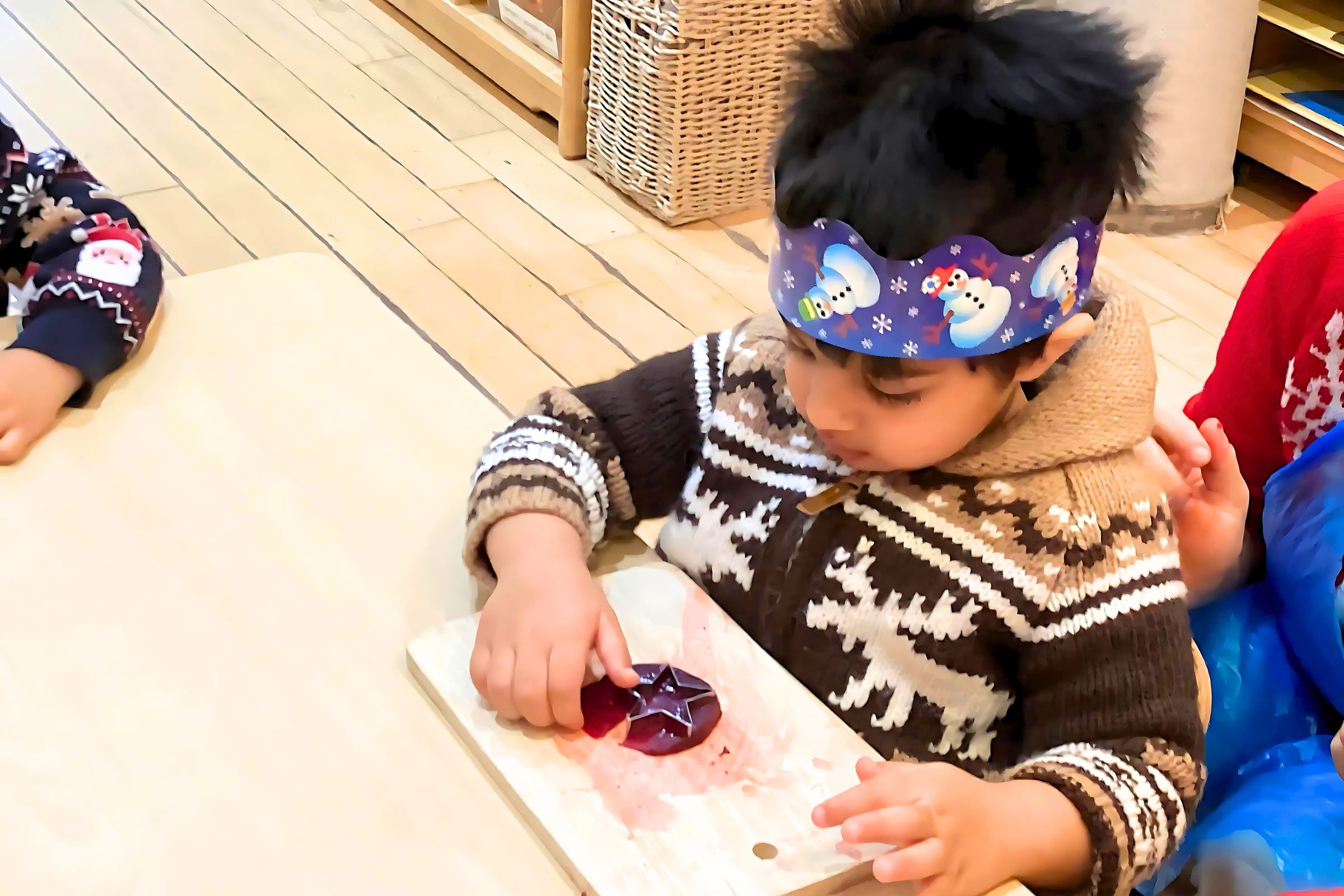 A preschooler concentrating on serving food to peers during a weekly activity